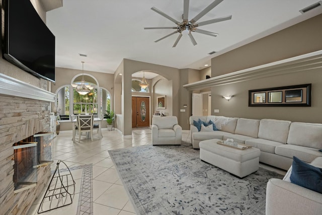 living room with light tile patterned floors, ceiling fan with notable chandelier, and a fireplace