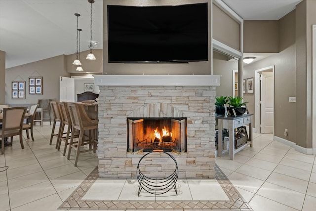 living room featuring lofted ceiling, light tile patterned floors, and a stone fireplace