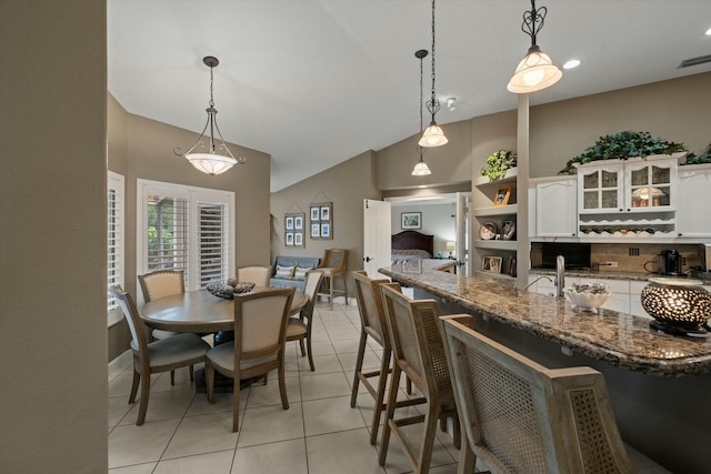 interior space featuring light tile patterned floors, decorative light fixtures, dark stone counters, and white cabinets