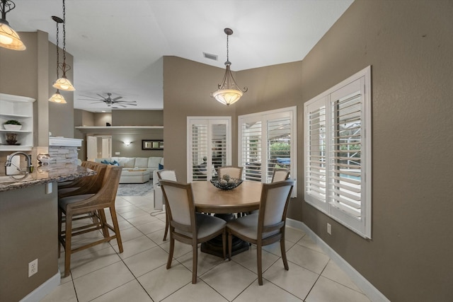 tiled dining area featuring ceiling fan, lofted ceiling, and sink