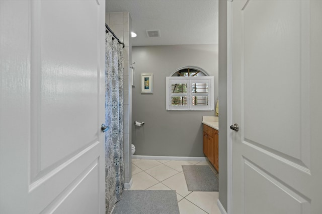 bathroom with vanity, toilet, tile patterned flooring, and a textured ceiling