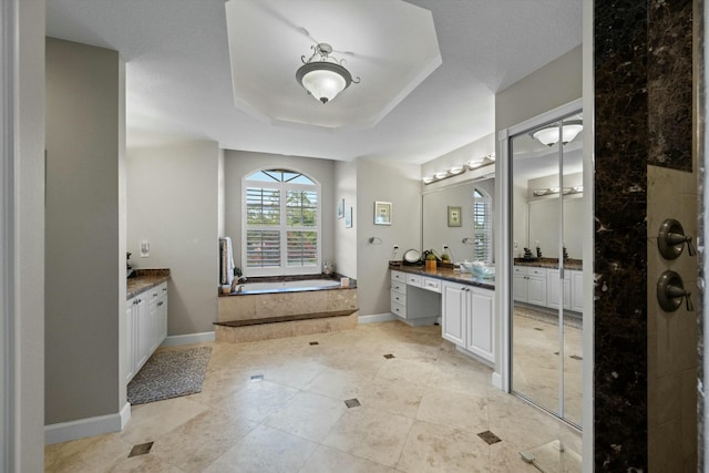 bathroom featuring vanity, tiled tub, and a raised ceiling