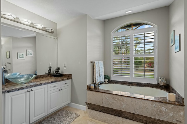 bathroom featuring vanity, tile patterned floors, tiled bath, and a healthy amount of sunlight