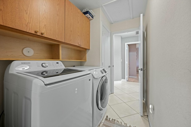 laundry room featuring light tile patterned floors, washer and clothes dryer, and cabinets