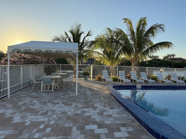 pool at dusk featuring a patio area