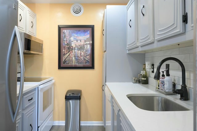 kitchen featuring appliances with stainless steel finishes, sink, white cabinets, and backsplash