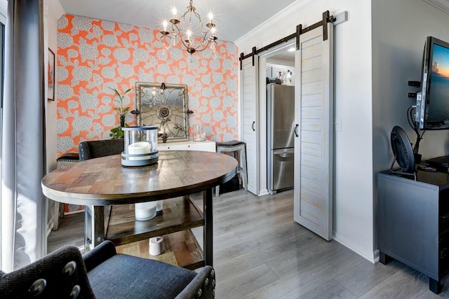 dining space with crown molding, a barn door, a chandelier, and light hardwood / wood-style floors