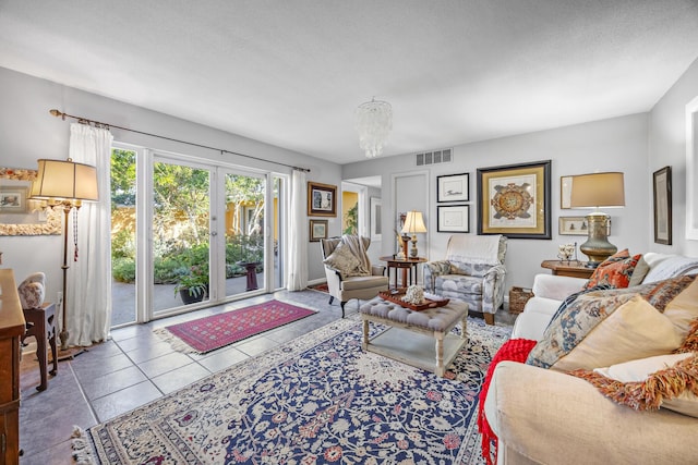 living room featuring a notable chandelier, tile patterned floors, and a textured ceiling