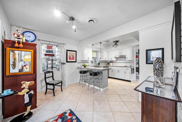 kitchen featuring a breakfast bar, ceiling fan, white cabinetry, light tile patterned flooring, and kitchen peninsula