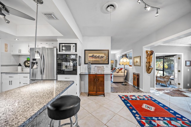 kitchen with light stone countertops, white cabinetry, appliances with stainless steel finishes, and light tile patterned floors