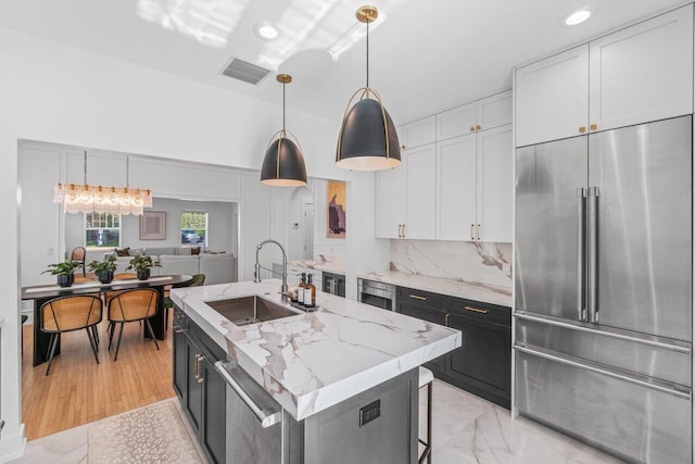 kitchen featuring white cabinetry, sink, hanging light fixtures, a kitchen island with sink, and stainless steel appliances