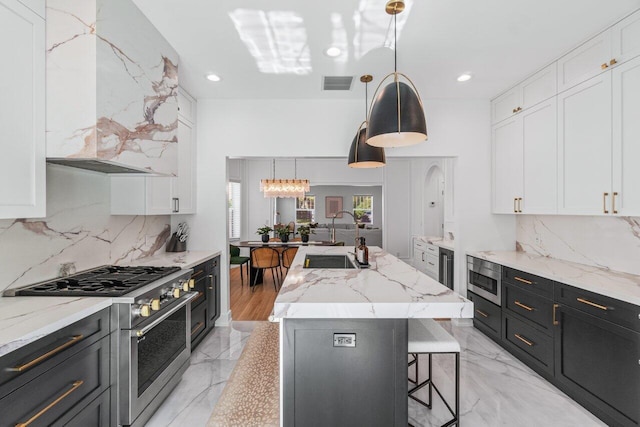 kitchen featuring white cabinetry, stainless steel appliances, and a center island with sink