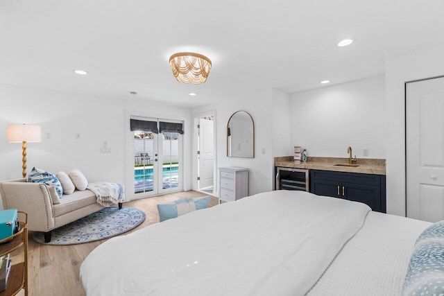 bedroom featuring light hardwood / wood-style flooring, beverage cooler, access to outside, wet bar, and french doors