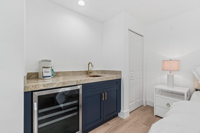 bar featuring blue cabinets, sink, wine cooler, and light hardwood / wood-style flooring