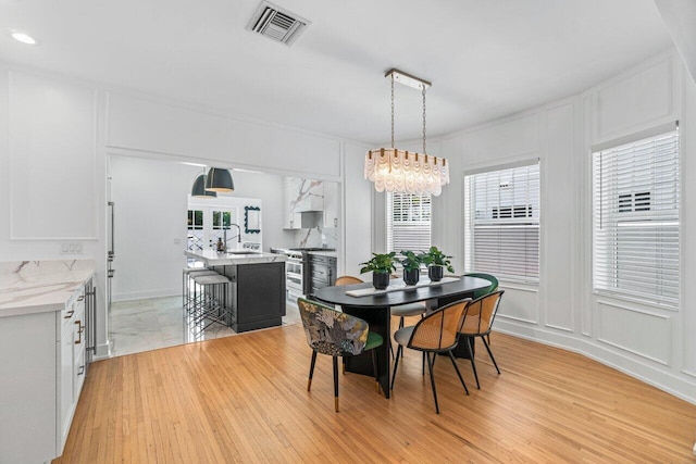 dining space featuring sink, a notable chandelier, and light hardwood / wood-style floors