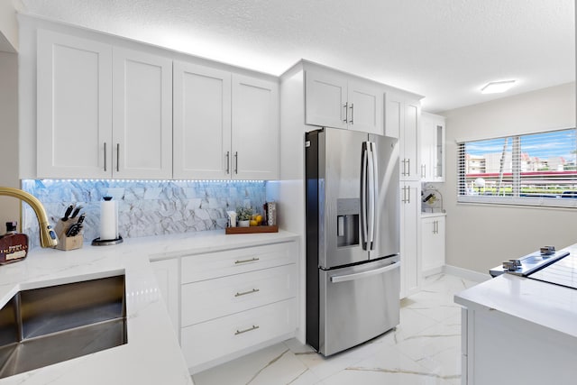 kitchen with white cabinetry, decorative backsplash, a textured ceiling, and stainless steel fridge with ice dispenser