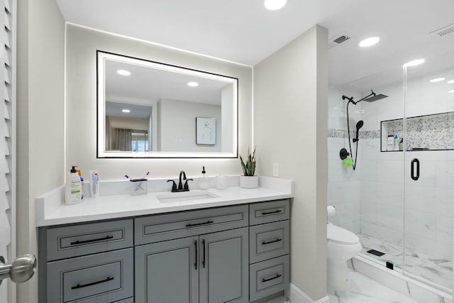 bathroom featuring vanity, a shower with door, and toilet