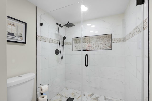 bathroom featuring a shower with door and toilet