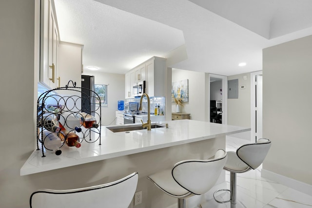 kitchen featuring white cabinetry, appliances with stainless steel finishes, a kitchen breakfast bar, and kitchen peninsula