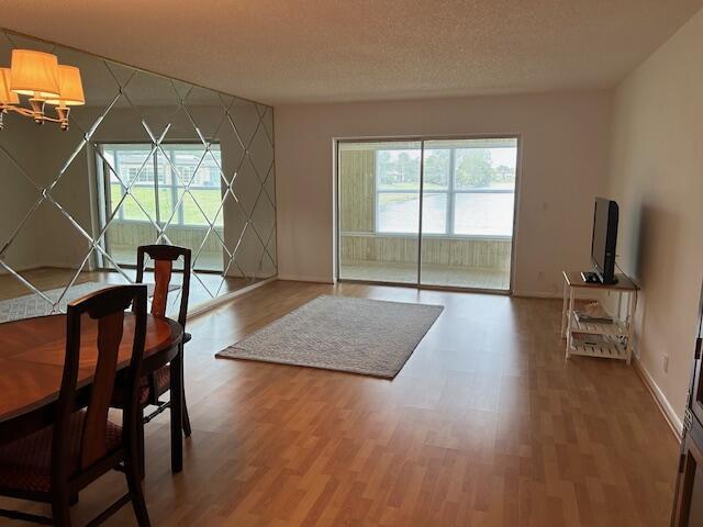 dining area with a textured ceiling, an accent wall, wood finished floors, and baseboards