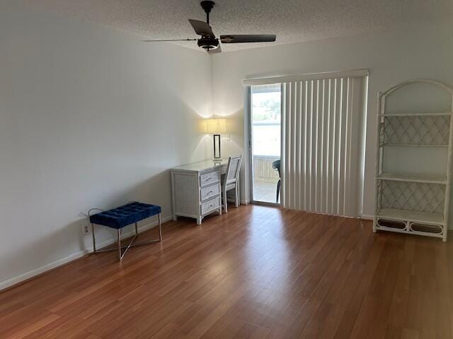 unfurnished office with baseboards, a textured ceiling, a ceiling fan, and wood finished floors