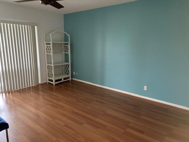 unfurnished room featuring a ceiling fan, baseboards, and wood finished floors