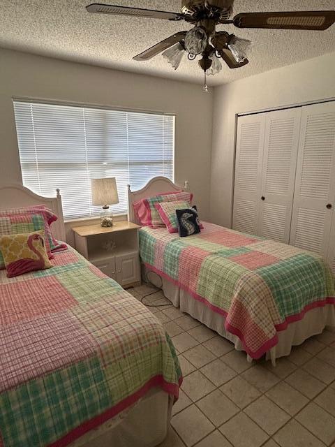 bedroom with a textured ceiling, ceiling fan, multiple windows, and a closet