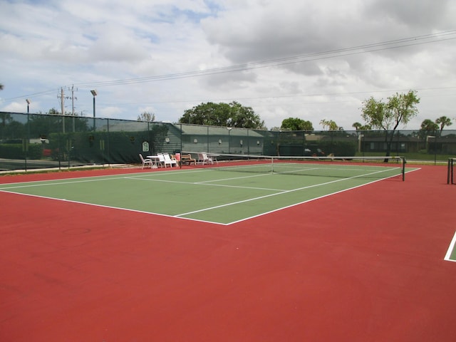 view of tennis court with community basketball court and fence