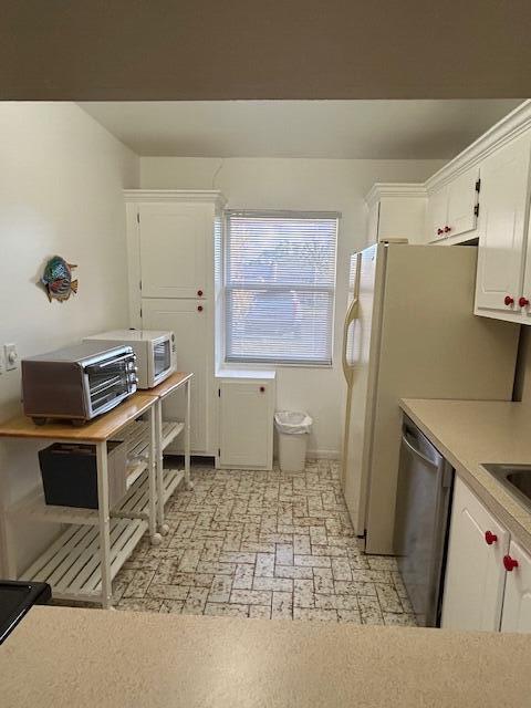 kitchen featuring light countertops, white cabinets, and dishwasher