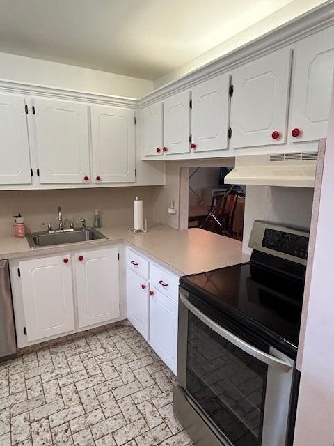 kitchen with light countertops, under cabinet range hood, white cabinetry, and electric range