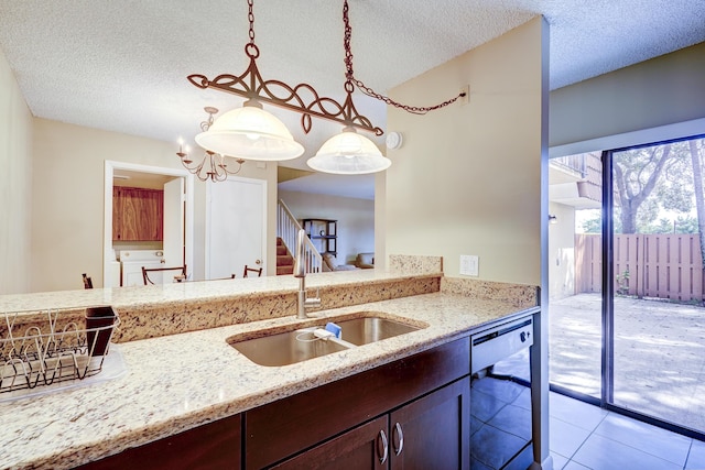 kitchen with hanging light fixtures, light stone countertops, sink, and dishwashing machine