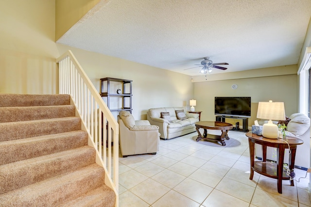 living room with ceiling fan, a textured ceiling, and light tile patterned floors