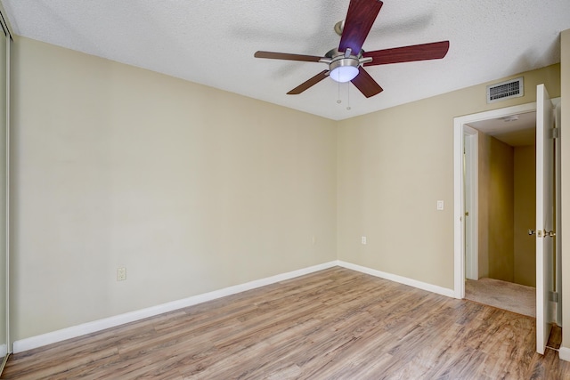 empty room featuring ceiling fan, light hardwood / wood-style flooring, and a textured ceiling