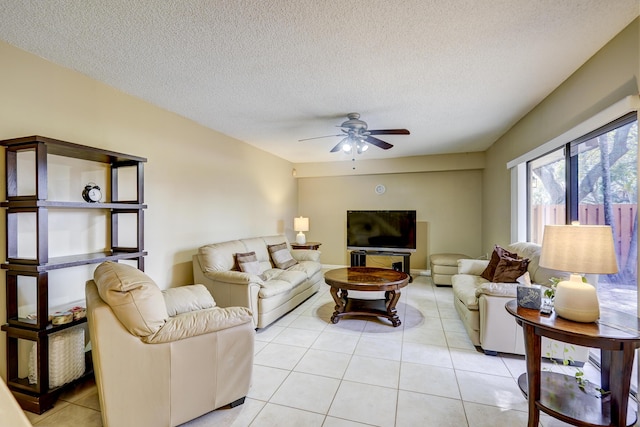 living room featuring ceiling fan, a textured ceiling, and light tile patterned floors