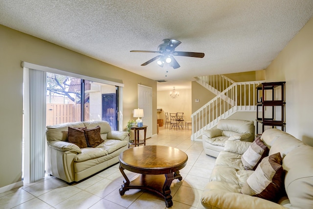 living room with ceiling fan with notable chandelier, a textured ceiling, and light tile patterned floors