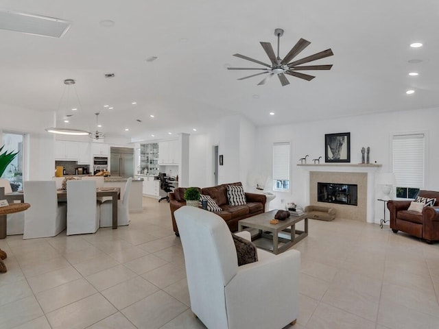 living room featuring ceiling fan, light tile patterned floors, and a high end fireplace