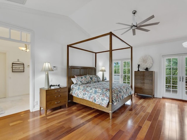 bedroom featuring lofted ceiling, access to exterior, wood-type flooring, ornamental molding, and french doors