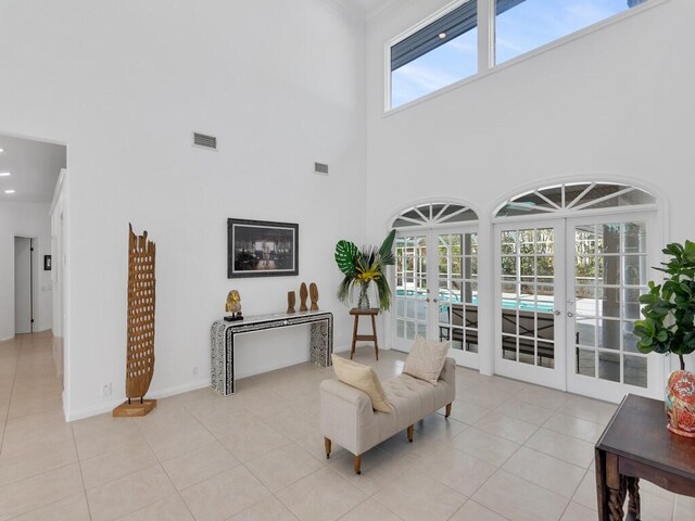 sitting room with a towering ceiling, light tile patterned floors, and french doors