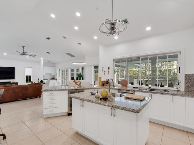 kitchen with light stone counters, hanging light fixtures, and a center island with sink