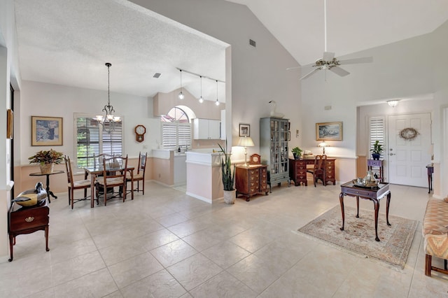 living room featuring light tile patterned floors, ceiling fan with notable chandelier, high vaulted ceiling, and a textured ceiling