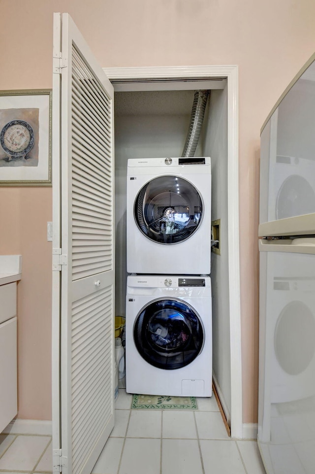 washroom with stacked washer / drying machine and light tile patterned floors