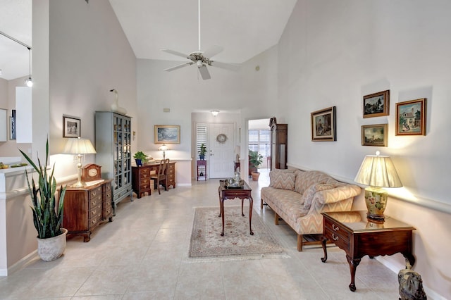 living room featuring ceiling fan, light tile patterned floors, and a high ceiling