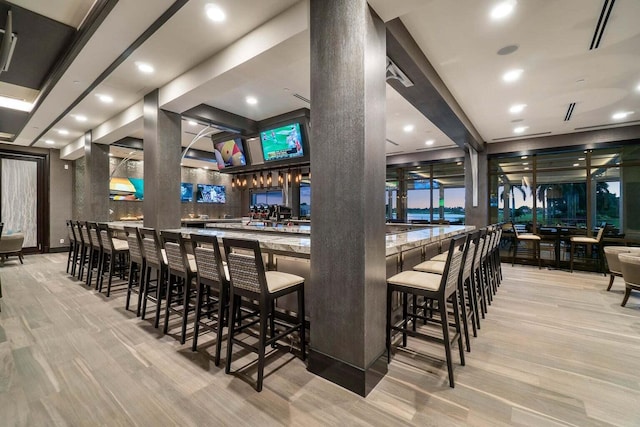 bar featuring light hardwood / wood-style floors and decorative columns