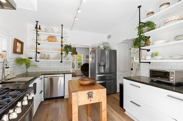 kitchen with white cabinetry, decorative backsplash, appliances with stainless steel finishes, and wood-type flooring