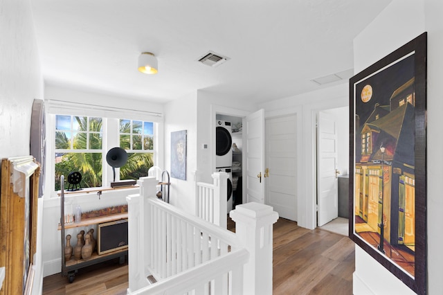 bedroom with hardwood / wood-style flooring and stacked washer and clothes dryer