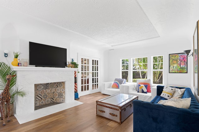 living room featuring a fireplace, wood-type flooring, french doors, and a textured ceiling