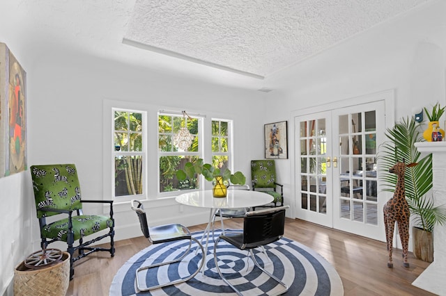 living area featuring hardwood / wood-style flooring, a textured ceiling, and french doors