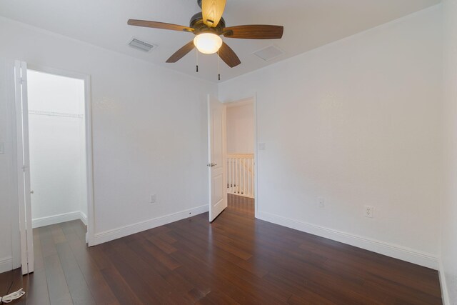 empty room featuring ceiling fan, a wealth of natural light, and dark hardwood / wood-style flooring