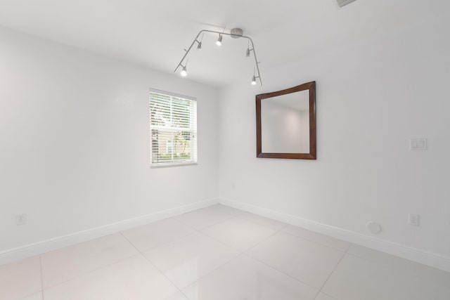 tiled empty room featuring rail lighting