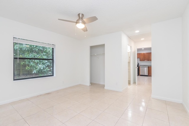 spare room with ceiling fan, a textured ceiling, and light tile patterned floors